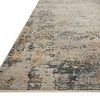 Close-up side angle of Axel beige rug showing low polyester pile texture and abstract blue-beige pattern.