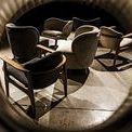 Group of Valerie Chairs in varied fabric colors, displayed in dimly lit concrete floor room with dramatic shadows