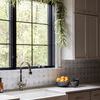 Close-up side angle of grey daisy stoneware planter and fruit bowl on kitchen counter near window with greenery