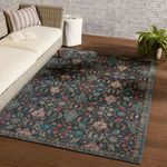 Rug styled in indoor setting with wicker sofa, white cushion, and wooden flooring