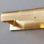 Close-up of the aged brass finish and adjustable arm bracket of the Oneonta picture light mounted on gray wall
