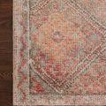 Close-up top-down view of rug corner showing detailed diamond and border pattern in warm red and orange tones on dark wood...