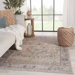 Rug laid out in living room setting with beige couch, throw blanket, and knitted pouf