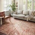 Saban Rust / Beige Rug styled in a bright living room under a modern beige sofa and leather chair