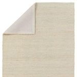 Back corner of the rug folded over showing underside material and edge binding