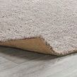 Corner flipped up to reveal underside backing fabric and looped jute texture on light flooring