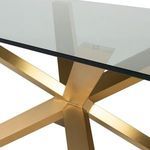 Close-up of gold metal base junction with brushed finish supporting clear glass tabletop