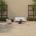 Kuna Outdoor Sofa styled in patio setting on striped rug with side chair and black coffee table
