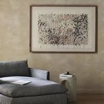 Painting hung above a gray sectional sofa and concrete side table in a beige textured room