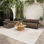 Manon Outdoor Side Table situated on outdoor patio with greenery, next to woven lounge furniture