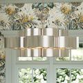 Close-up of Grand Lotus Chandelier hanging with floral wallpaper and window in background showing metallic curve detail