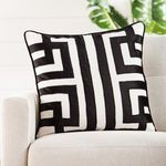 Pillow styled on beige sofa with green plant backdrop showing full geometric pattern