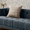 Fern Ivory Beige pillow sitting on a blue tufted velvet sofa against leafy wallpaper
