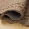 Side angle view showing rug’s thickness and textured wool fibers with curved scalloped edges