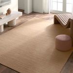 Rug styled in a bright room with hardwood floors, a modern chair, and soft round pouf