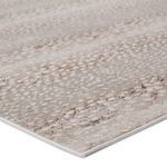 Close-up on corner showing low pile texture and tightly finished edge of gray and brown spotted animal print rug