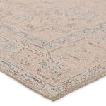 Close-up of rug corner showing low-pile polyester texture and stitched edges in beige and light blue tones