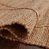Rolled edge of natural jute rug displaying flexibility and thick textured weave