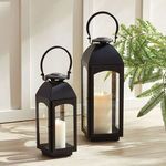 Two sizes of Antoinne Outdoor Lanterns side by side indoors with green plant and wood floor