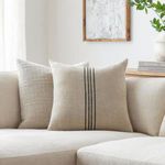 Pillow styled on beige sofa with vertical black stripes visible in neutral living room setting