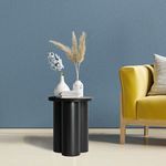 Obsidian Cylinder End Table styled in living room next to yellow armchair with vases and books on top