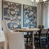 Chair positioned at end of dining table in a room with floral wall art and wood floor