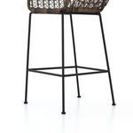 Close-up of black iron frame foot caps and support bars beneath wicker seat