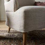 Side view highlighting chair’s armrest shape and fabric tail of skirt