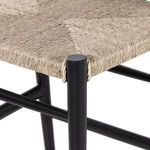 Detailed view of black teak curved armrest and woven seat intersection