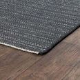 Corner view of charcoal rug on wooden floor highlighting edge and flat weave texture