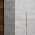 Rug corner lying flat on dark wood floor showing border detail of geometric pattern