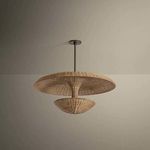 Draco Pendant unlit in neutral room, emphasizing the woven wicker texture and Bronze Leaf stem from a slight angle