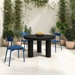 Outdoor dining area with three Kent chairs surrounding round black table on beige rug