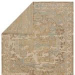 Rug corner folded to reveal solid khaki backing with slightly muted pattern underneath.