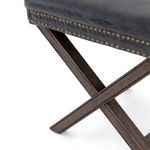 Close-up of smooth black leather seat with double row of brass nail heads wrapped around edge