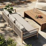 Outdoor patio scene with Sherwood sofa paired with wooden coffee table and garden greenery