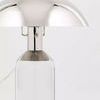 Large table lamp angled left with reflective metal shade and transparent glass base