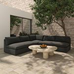 Miles sectional styled outdoors on tiled patio with stone wall and leafy tree in background