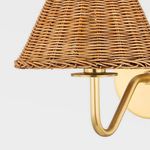 Close-up of woven rattan shade with aged brass holder and arm