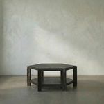 Hexagonal Yuhuda Coffee Table in cinder black mindi wood with lower shelf and thick legs, set against plain background