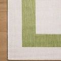 Top view close-up of rug corner showing woven texture on green border and ivory center