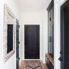 Wynter rug laid in hallway with light wood floor, black door, and framed mirror