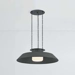 Woodrow Pendant hanging lit with warm light showing glowing opal shade inside dark reflector