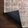 Rug corner flipped up to show black backing material contrasting with warm-toned front