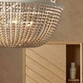 Close-up of chandelier bead strands in front of wooden cabinet with open door and decorative vases