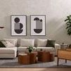 Interior wall with black and white framed geometric art paired with plants and wood decor