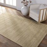 Esdras rug styled in a living room with armchair, hardwood floor, and large white vase