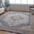 Rug displayed in a modern living room with gray armchair, sofa, and wooden floor under natural light