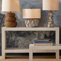 Three decorative lamps including Mabrouka Table Lamp styled on white console against artistic blue abstract wall