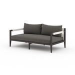 Sherwood sofa angled from front left showing two large charcoal back cushions and woven strap armrests.